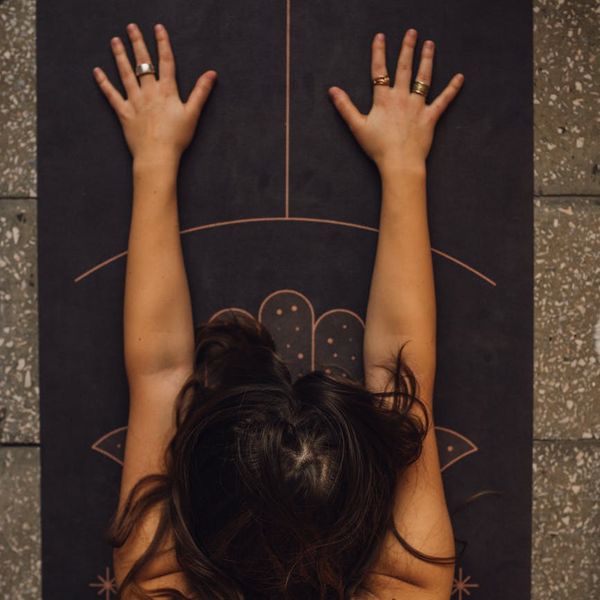 Person stretching on a yoga mat with a serene background.
